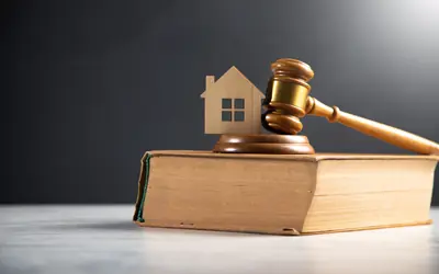 Mazo de juez, casa de madera y libro de leyes