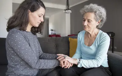Daughter holding her elderly mother's hands at home