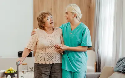 Caregiver helping an elderly woman walk at home