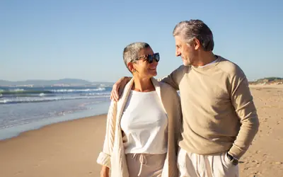 Smiling retired couple walking along the beach