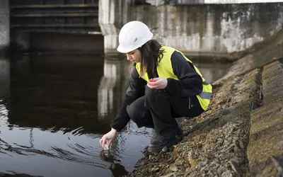 Técnica ambiental tomando una muestra de agua