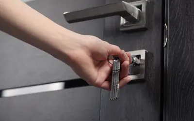 Hand locking a home's front door with a key