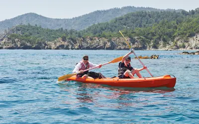 Two people paddling an orange kayak at sea