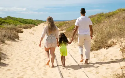 Family walking hand in hand towards the beach